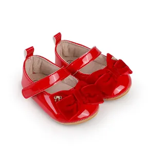 Primer plano de zapatos de princesa rojos para bebé con lazo de terciopelo y charol.