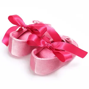 Détail de chaussures de bébé en velours rose avec nœuds en ruban de satin fuchsia