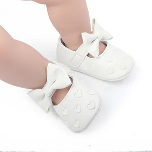 Nahaufnahme von weißen Baby-Prinzessin-Schuhen mit süßer Schleife und Herzstickerei
