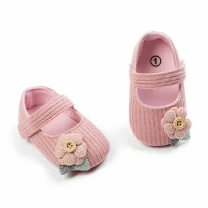 Detailansicht von rosa gestrickten Babyprinzessinnenschuhen mit Blumen und Knöpfen