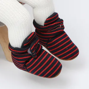Gros plan sur des bottes de bébé rayées en polaire avec motifs rouge et bleu vif.