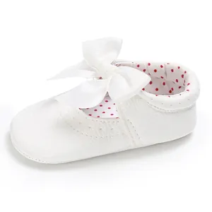 Detalle de zapato de princesa blanco para bebé con lazo grande y forro de lunares rojos