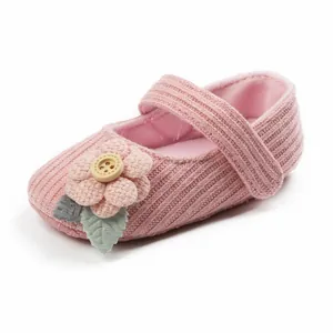 Nahaufnahme eines rosa gestrickten Baby-Prinzessinnenschuhs mit Blume und Knopf