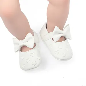 Nahaufnahme von weißen Baby-Lauflernschuhen mit Herzmuster und Schleifendetail für Mädchen