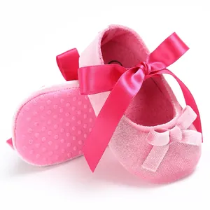 Détail des chaussures de bébé en velours rose avec un grand nœud en satin