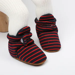 Gros plan de bottines d'hiver rayées rouge et bleu pour bébé avec semelle souple