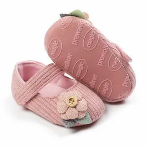Detailaufnahme der rosa gestrickten Babyschuhe mit Stoffblume und Holzknopf-Detail