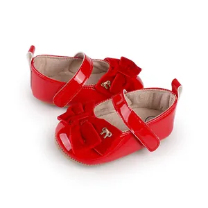 Detalle de los zapatos de princesa de charol rojo para bebé con adorno de lazo de terciopelo