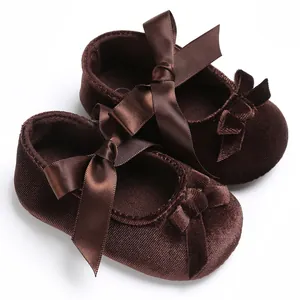 Vue détaillée de chaussures pour bébé en velours marron avec d'élégants nœuds en satin.
