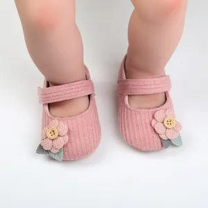 Nahaufnahme von weichen rosa gestrickten Babyschuhen für Mädchen mit Blumen und Knöpfen
