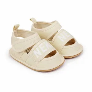 Close-up of cream baby walking sandals with NEK print and strap