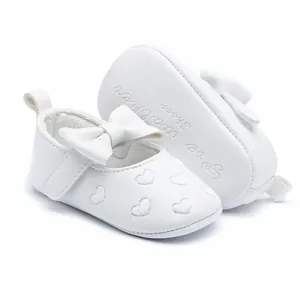 Macro detail of white baby walker shoes featuring heart embroidery and a bow decoration