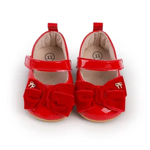 Detalle de zapatos de princesa para bebé en charol rojo con lazos grandes de terciopelo