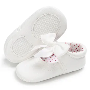 Vista detallada de zapatos blancos de bebé para aprender a caminar con lazo y suela antideslizante
