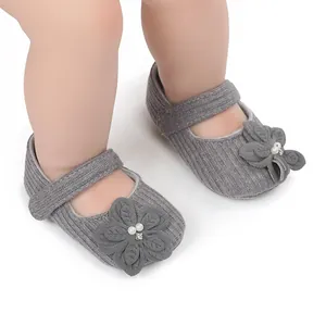 Dettaglio di scarpe da principessa per neonati grigie con suola morbida e fiori eleganti