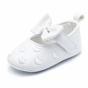 Elegant white baby walker shoes featuring heart embroidery and a large decorative bow tie