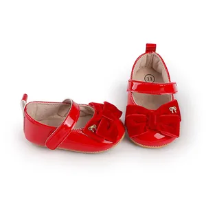 Detalle de zapatos de princesa para bebé en charol rojo con un lazo de terciopelo.