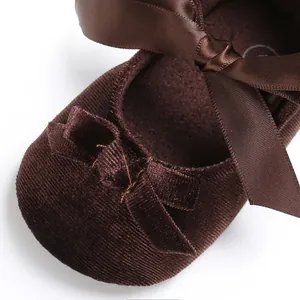 Détail macro de chaussures bébé en velours côtelé marron avec nœuds en satin