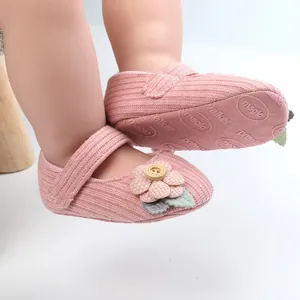 Detail von rosa gestrickten Babyschuhen mit Blumenakzent und weichen rutschfesten Sohlen.