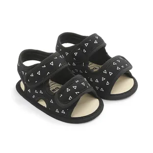 Close-up of stylish black baby sandals with white triangle pattern and double velcro straps