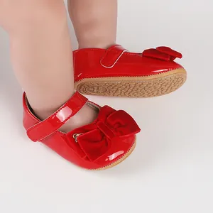 Detalle de zapatos de princesa para bebé en charol rojo con lazo de terciopelo y suela.
