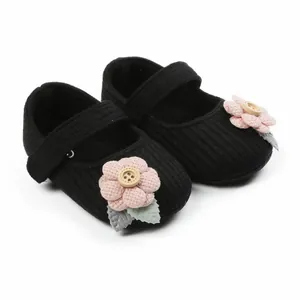 Detailansicht der schwarzen Baby-Strickschuhe mit dekorativen rosa Stoffblumen