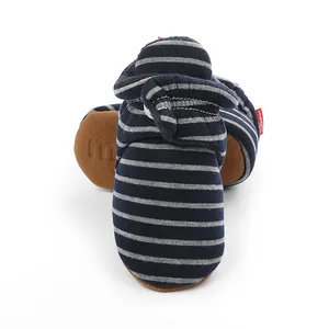 Détail de chaussons bébé rayés bleu marine et gris avec fermeture par bande auto-agrippante.