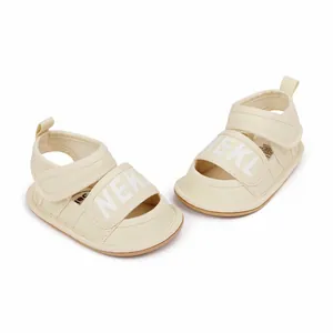 Close-up of beige infant sandals showing canvas texture and NEKL printed strap