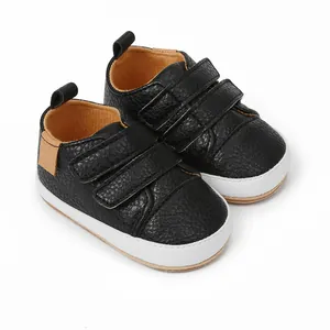 Close-up side view of black faux leather baby walking shoes with white soles and velcro straps