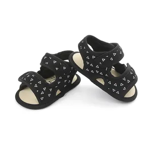 Detail showing black baby sandals with white triangle pattern and soft non-slip soles