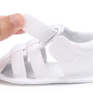 Detail view of adjustable velcro strap on white baby boy closed-toe sandals.