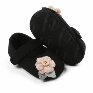 Detailansicht schwarzer Strickschuhe für Babymädchen mit rosa Stoffblume und weicher Sohle
