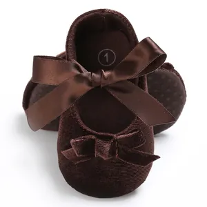 Gros plan sur des chaussures de marche pour bébé en velours marron avec nœuds