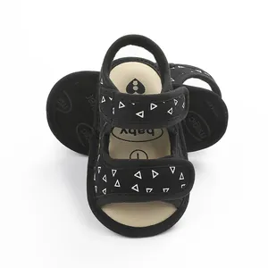 Detail view of black fabric baby sandals with white triangle print and velcro straps