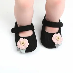Detailansicht schwarzer gestrickter Babyschuhe mit rosa Stoffblumen-Applikationen