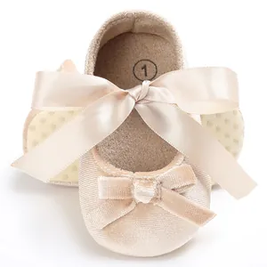Détail de chaussures pour bébé en velours champagne avec un grand nœud en satin