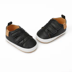 Detail of black faux leather baby pre-walker shoes with triple velcro straps and white sole.