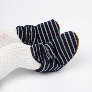 Gros plan de bottines d'hiver à rayures pour bébé avec des chaussettes blanches.
