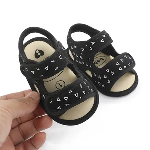 Close-up of black baby walking sandals with white triangle patterns and soft soles