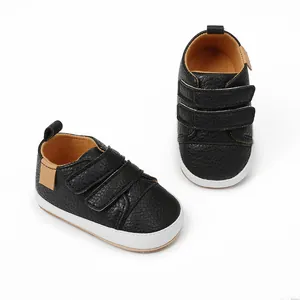 Detailed macro view of black faux leather baby sneakers with double velcro straps
