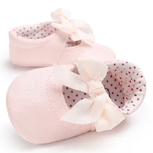 Primer plano de zapatos rosa de princesa para bebé con lazo crema y forro de lunares
