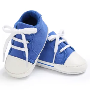 Nahaufnahme blauer Segeltuch-Babyschuhe mit weißen Schnürsenkeln und Zehenkappen