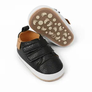 Detail view of black faux leather infant sneakers with non-slip patterned soles.