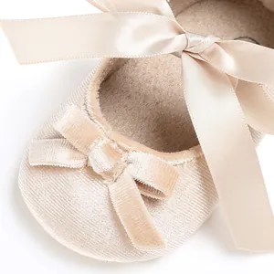 Détail en gros plan de chaussures bébé en velours champagne avec un grand nœud en satin