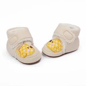 Nahaufnahme von beigen Baby-Winterschuhen mit süßem gelbem Entenmuster und Fleecefutter.