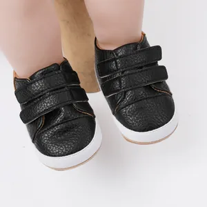 Macro view showing the texture and double velcro straps of black baby walking shoes.