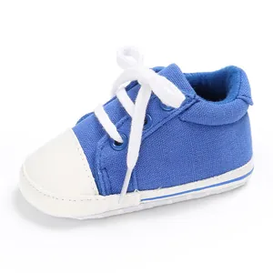 Nahaufnahme eines blauen Canvas-Babyschuhs mit weißen Schnürsenkeln und weicher Sohle