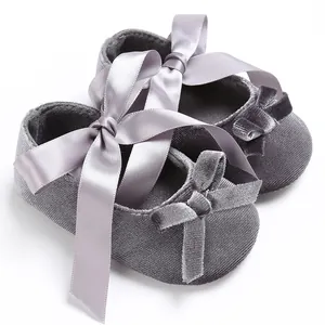 Gros plan sur des chaussures de bébé en velours gris avec des rubans en satin doux