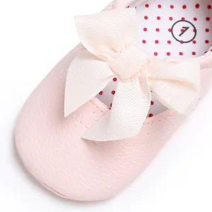 Primer plano de zapato rosa para bebé con lazo de cinta crema y acabado de textura suave