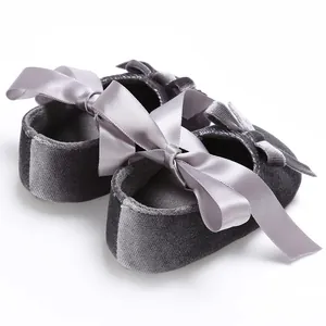 Détail de chaussures de marche pour bébé en velours gris avec un grand nœud en satin